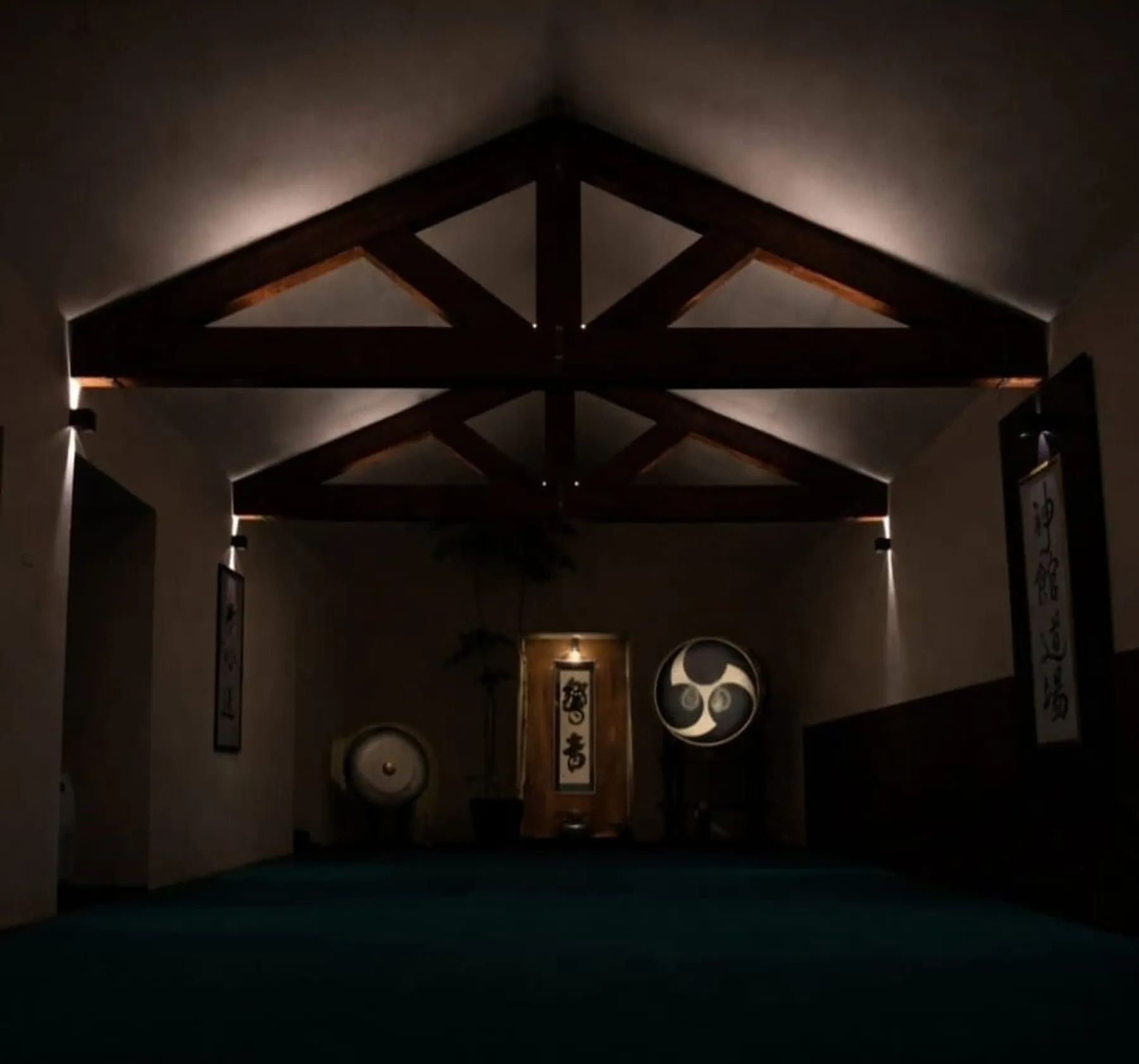 La sala del Dojo di sera: le capriate in legno illuminate e, sul fondo, il grande tamburo